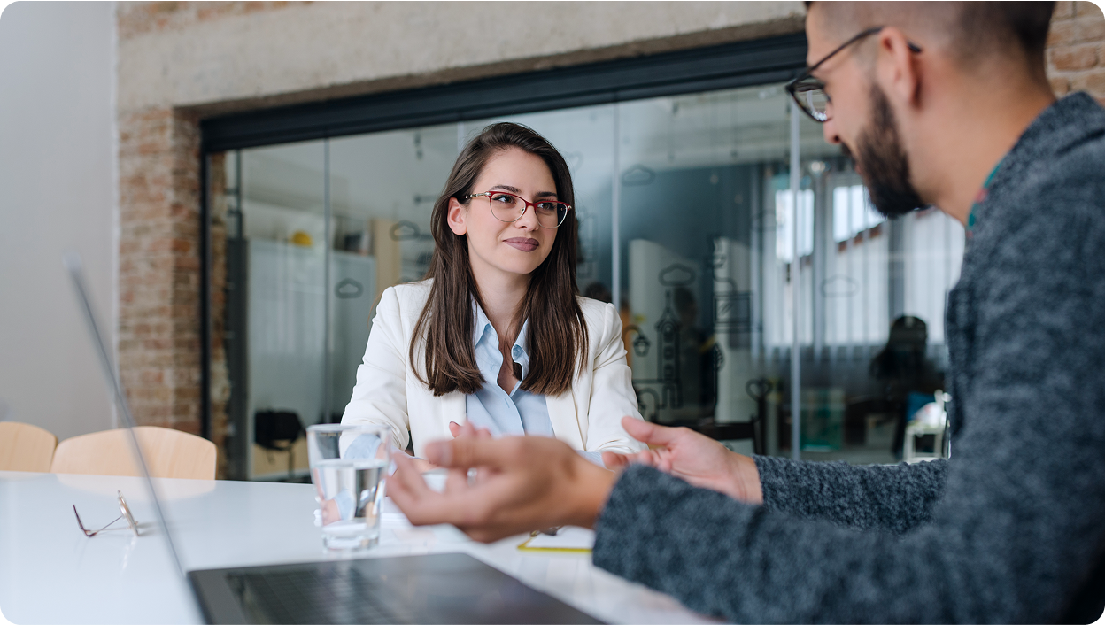 Two young professionals sitting in a boardroom having a discussion.